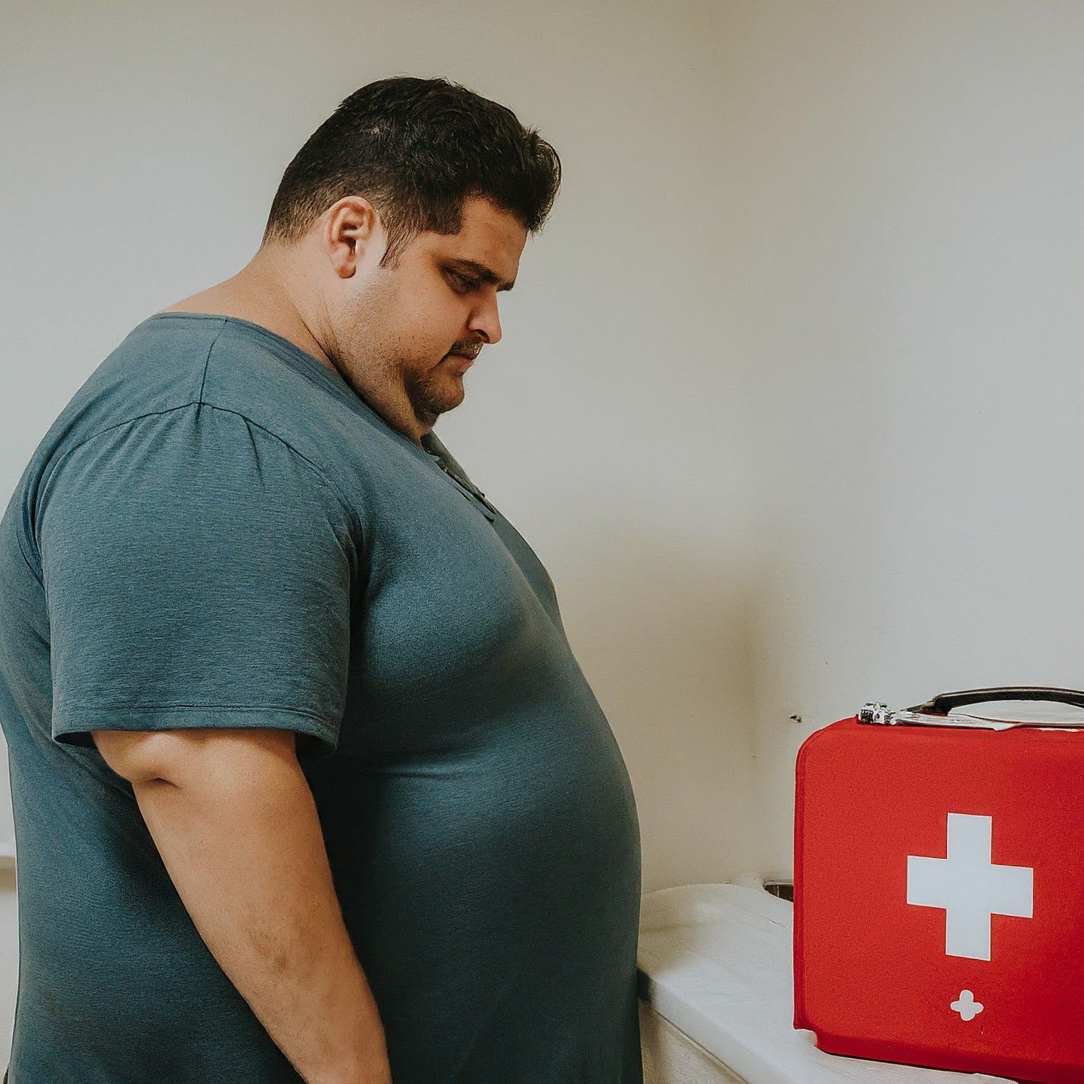 Obese man looking upset and frustrated about his weight gain caused by a sedentary lifestyle